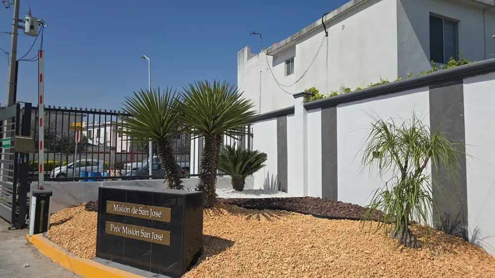 Acceso de residencial con palma y jardín de piedra