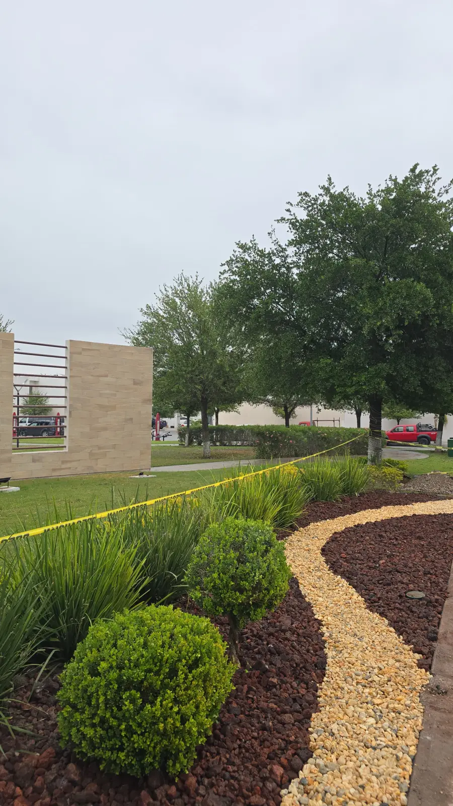Jardín con setos esféricos, piedra decorativa y árboles