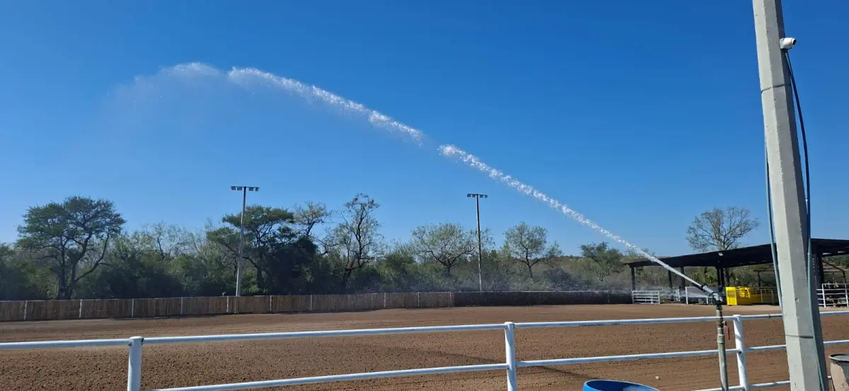 Cañón aspersor industrial creando un arco de agua sobre una arena