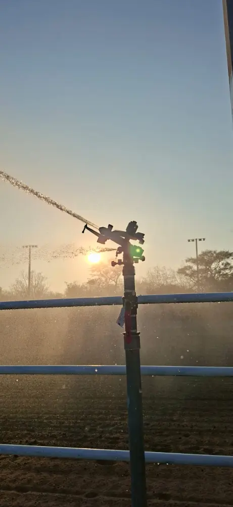 Aspersor agrícola al atardecer regando un campo